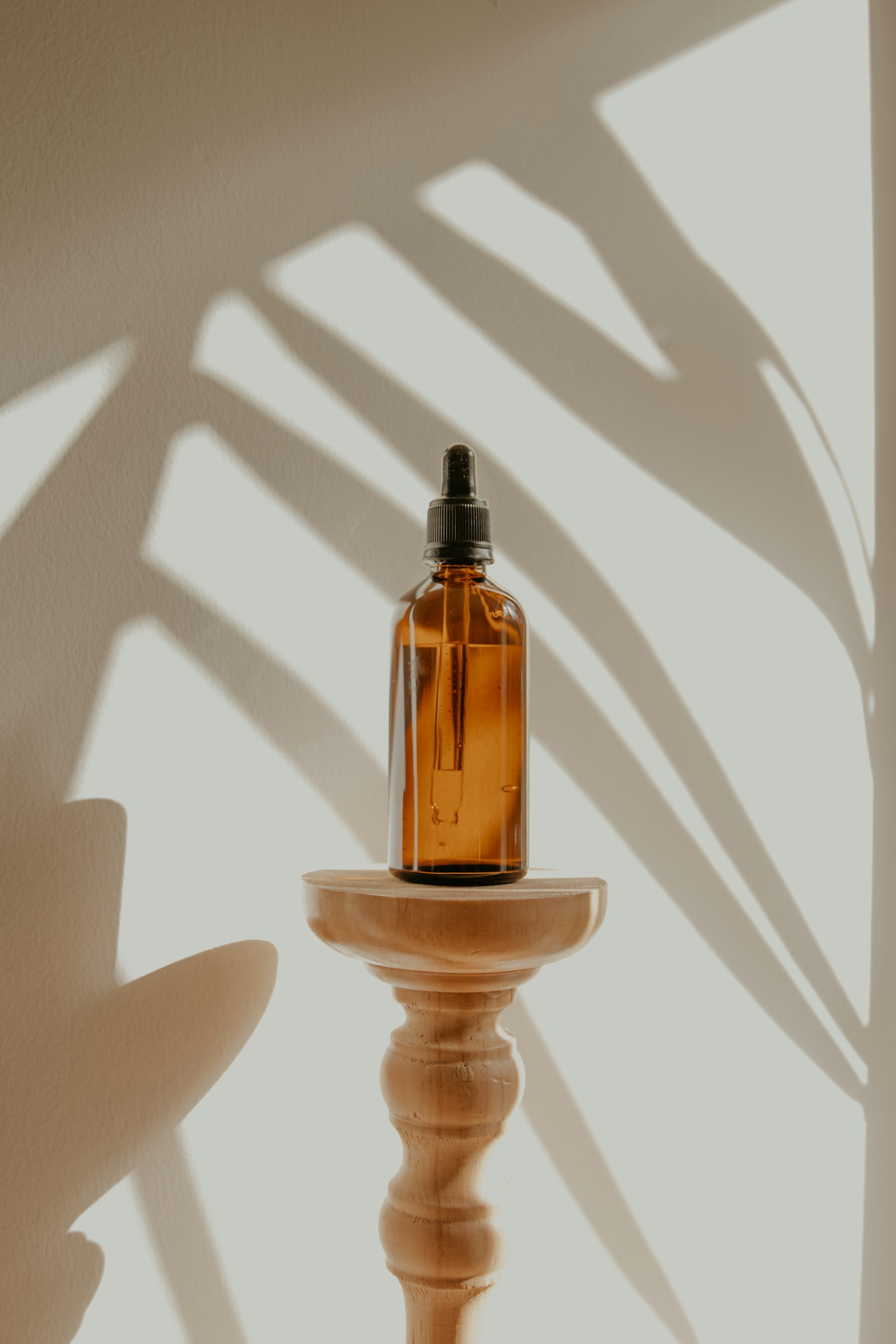 Amber serum bottle on a wooden pedestal