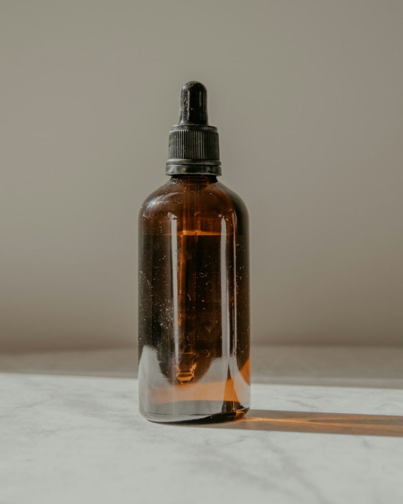 Amber glass dropper bottle of golden oil on a marble table