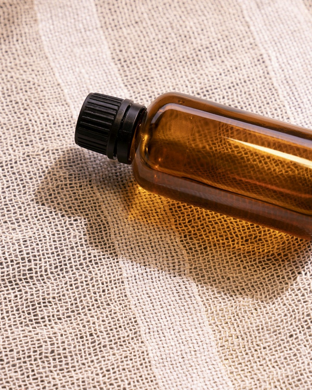 Amber glass bottle lying on natural linen