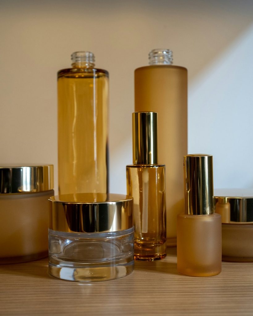 Amber glass bottles and jars with gold lids on a wooden shelf