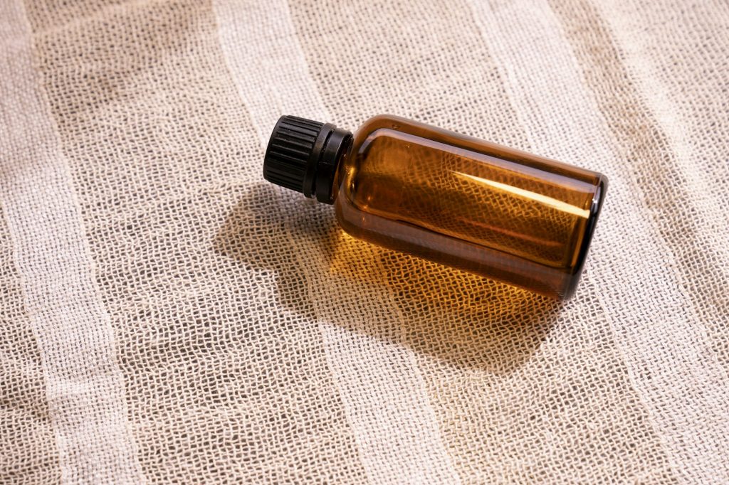 An unlabelled amber glass bottle lying on striped linen