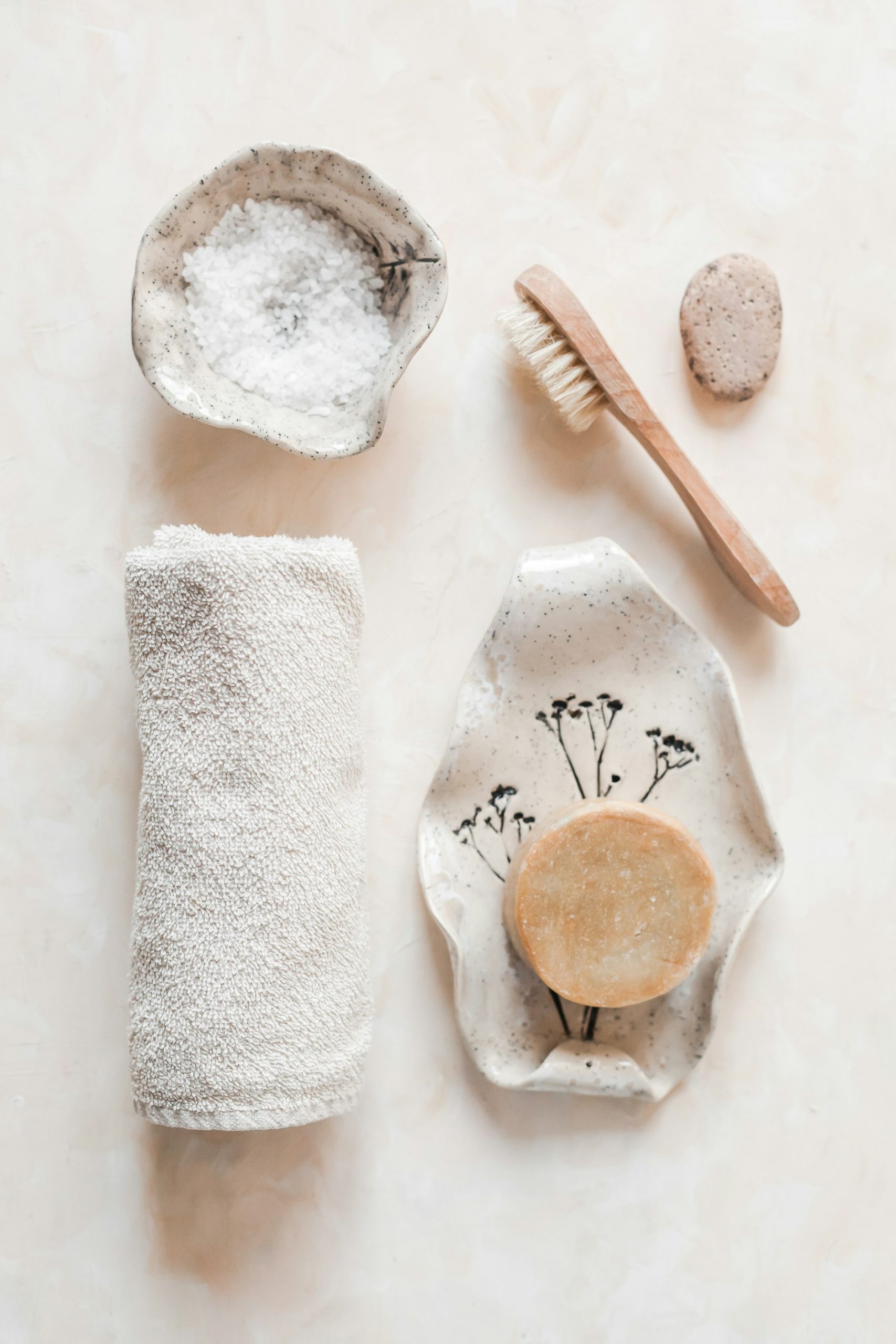 Bath salts in a ceramic dish beside a rolled towel, a brush and a round soap Bath salts in a ceramic dish beside a rolled towel, a brush and a round soap