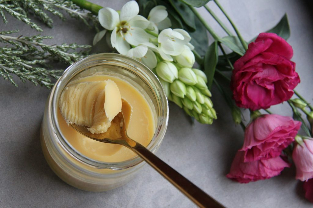 A jar of whipped white body butter with a wooden spoon