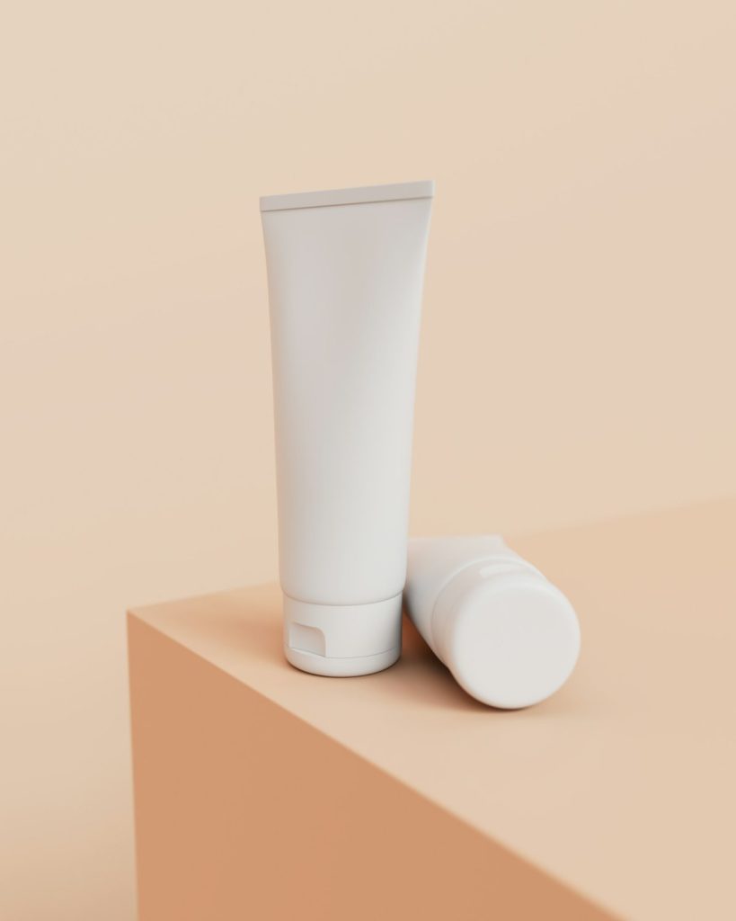 Two plain white cream tubes on a peach plinth